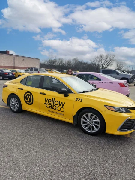 Professional photo of a yellow taxi cab with a black decal on the side that saids 
